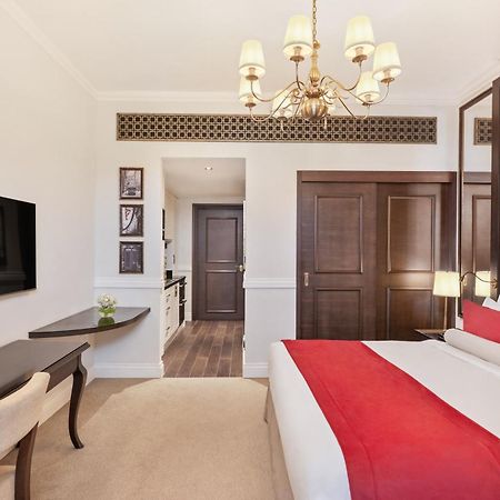 Dukes The Palm, A Royal Hideaway Hotel Dubai Esterno foto The photo shows a well-decorated hotel room. It features a large bed with a red and white color scheme, complemented by stylish pillows and a tufted headboard. A modern chandelier hangs from the ceiling, providing light. There is a flat-screen TV mou