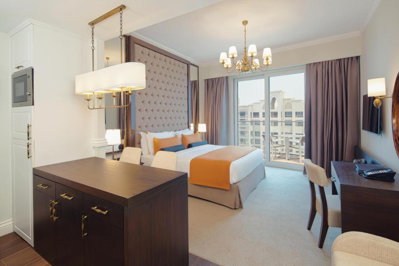 Dukes The Palm, A Royal Hideaway Hotel Dubai Esterno foto The photo shows a modern hotel room with a stylish design. The room features a large bed with orange and white bedding, complemented by a decorative headboard. There are two curtains framing a large window that allows natural light to fill the space.