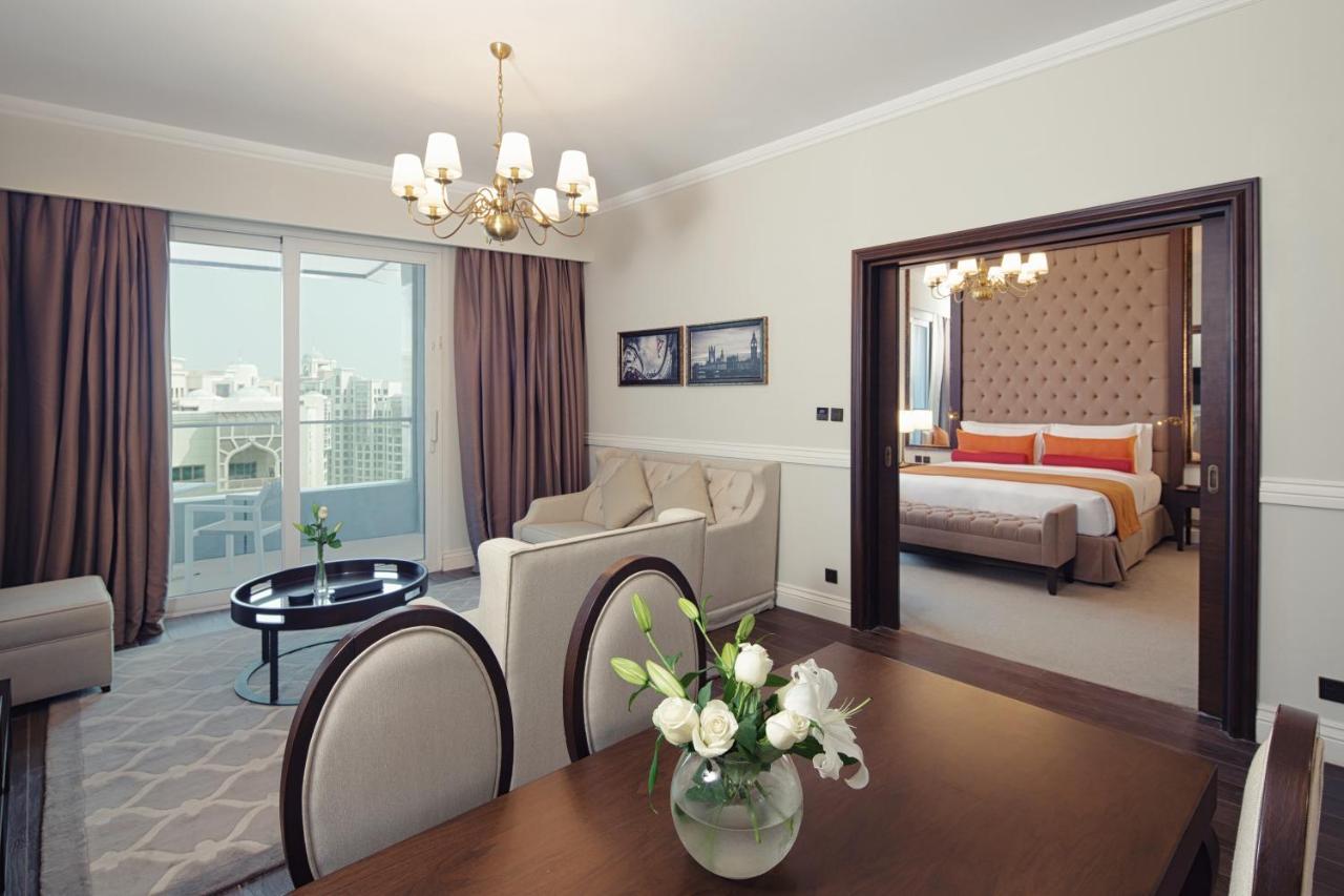 Dukes The Palm, A Royal Hideaway Hotel Dubai Esterno foto The photo depicts a well-furnished hotel suite or living space. In the foreground, there is a dining table with plush chairs and a vase of flowers. Beyond that, you can see a cozy living area with a sofa set and a coffee table, illuminated by a chand