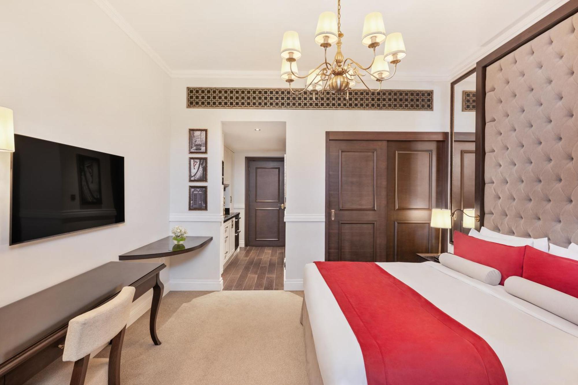 Dukes The Palm, A Royal Hideaway Hotel Dubai Esterno foto The photo shows a well-decorated hotel room. It features a large bed with a red and white color scheme, complemented by stylish pillows and a tufted headboard. A modern chandelier hangs from the ceiling, providing light. There is a flat-screen TV mou