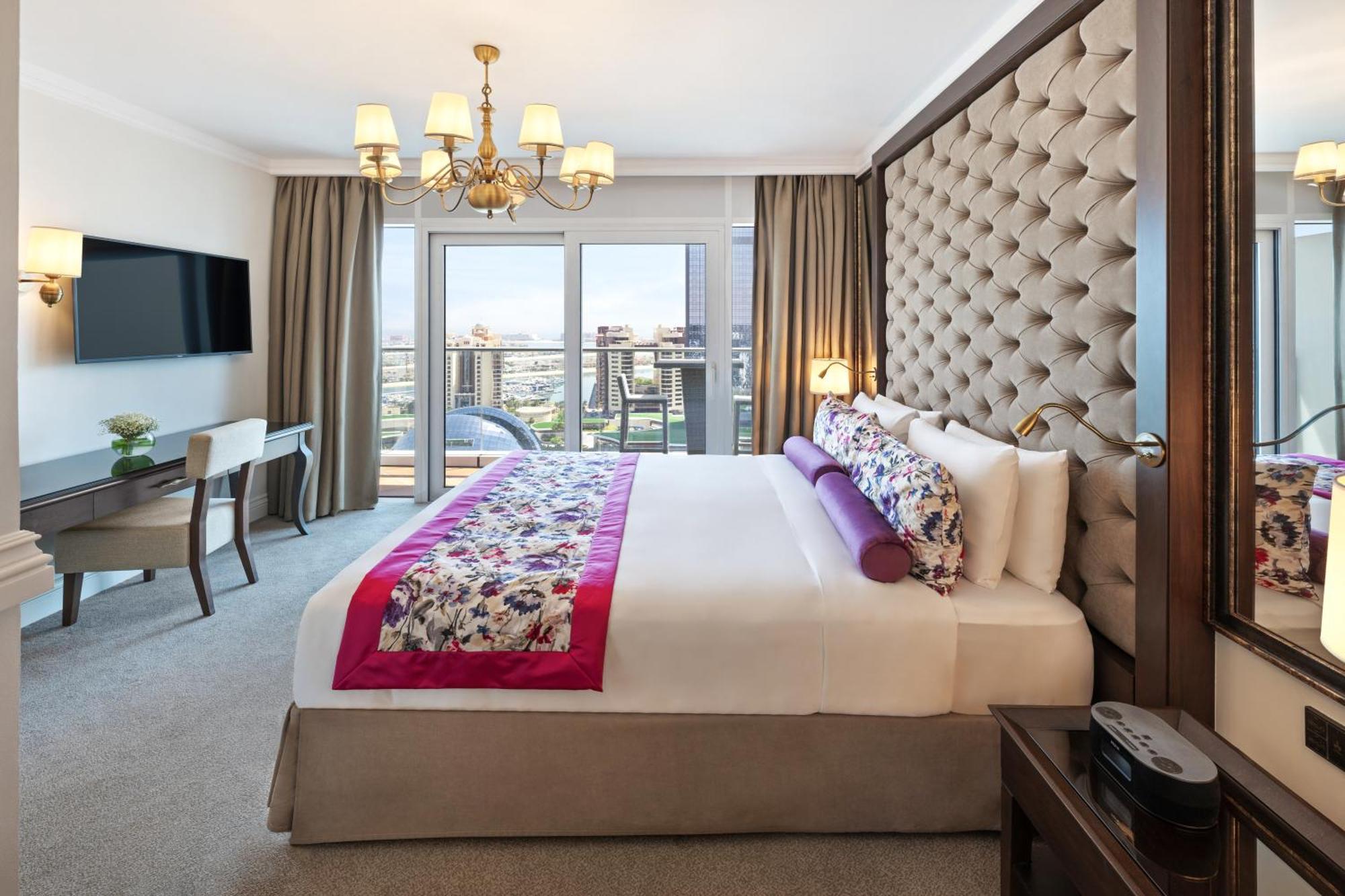 Dukes The Palm, A Royal Hideaway Hotel Dubai Esterno foto The photo depicts a luxurious hotel room. The prominent features include:

- A large bed with a tufted headboard, adorned with decorative pillows and a colorful bed runner.
- A spacious layout that includes a chic chandelier hanging from the ceiling.