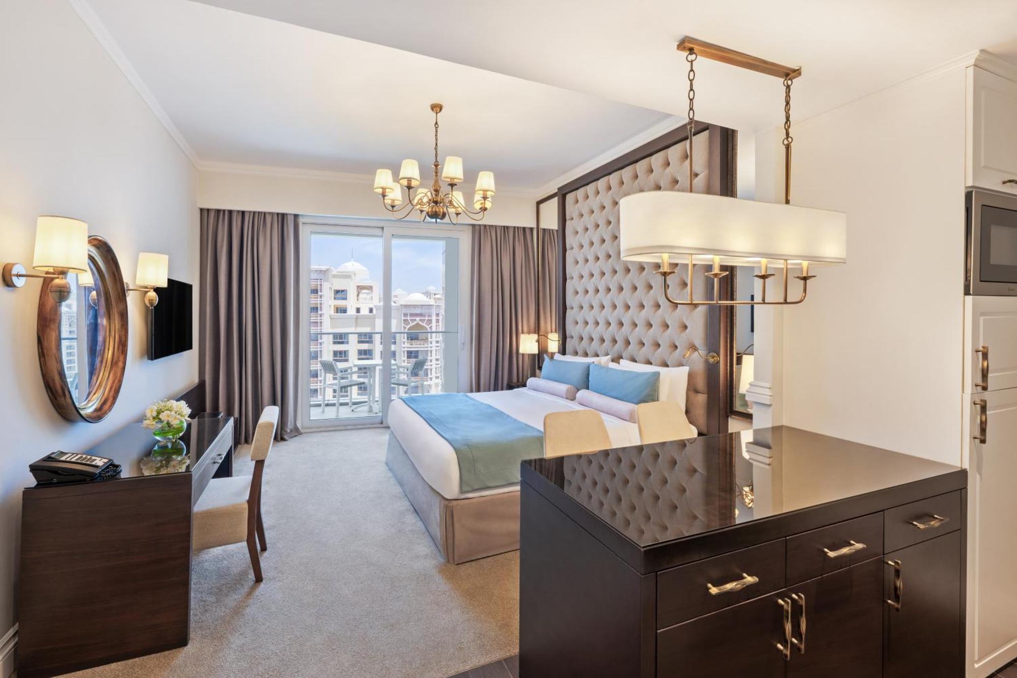 Dukes The Palm, A Royal Hideaway Hotel Dubai Esterno foto The photo shows a luxurious hotel room featuring modern decor. The room includes a large bed with a tufted headboard, soft bedding in light colors, and stylish furnishings. There is a desk and a chair in one corner, along with a decorative mirror and