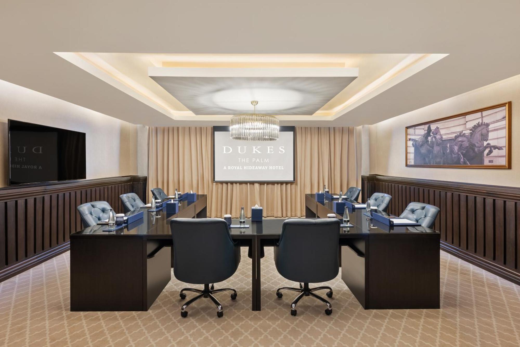 Dukes The Palm, A Royal Hideaway Hotel Dubai Esterno foto The photo shows a modern conference room designed for meetings. It features a large rectangular table in the center surrounded by several ergonomic chairs. On one side, there is a large projection screen displaying the word "DUKES." The room has eleg