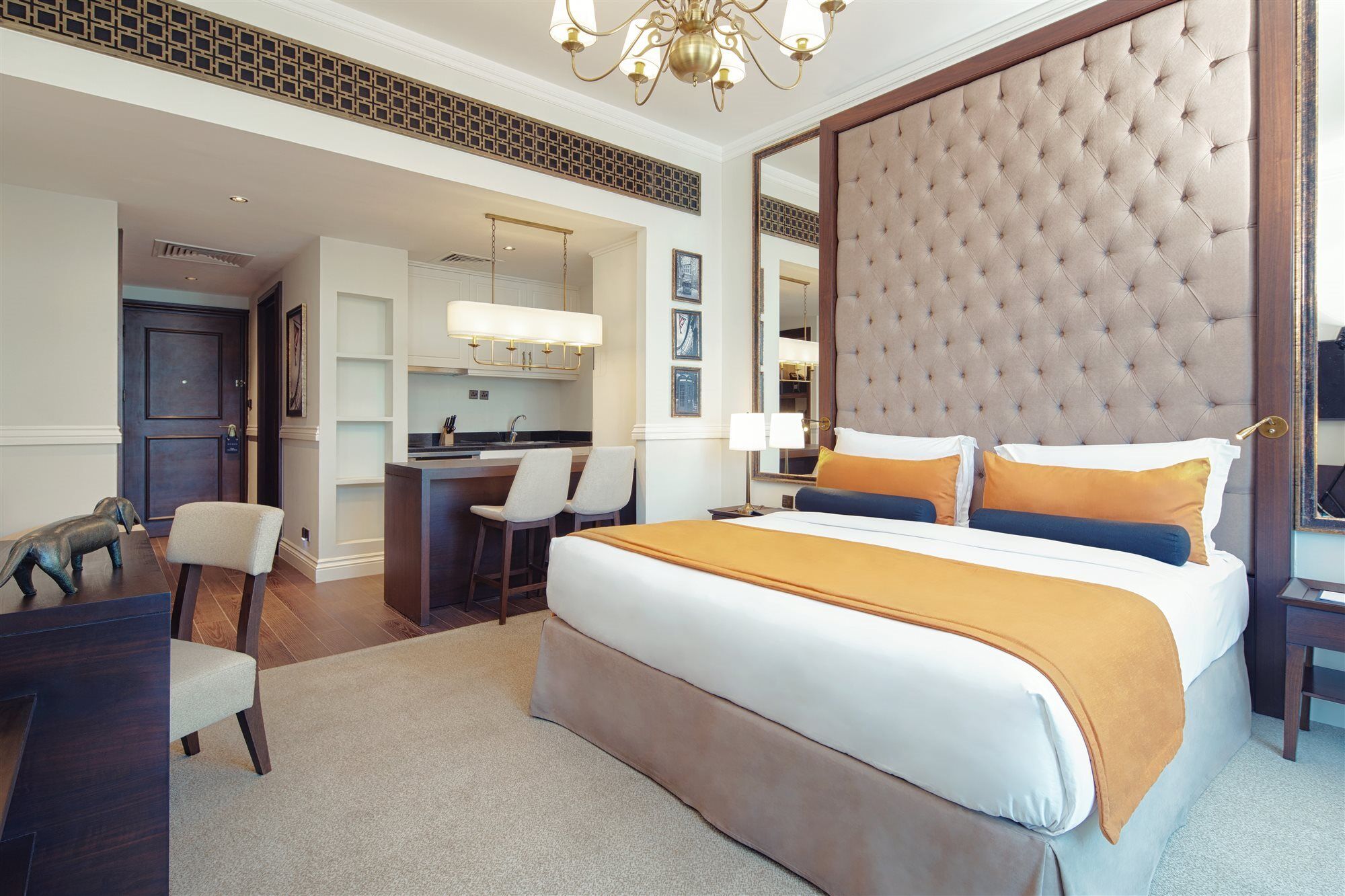Dukes The Palm, A Royal Hideaway Hotel Dubai Esterno foto The image shows a modern hotel room featuring a stylish design. In the center, there's a large bed with a tufted headboard upholstered in light brown, complemented by two decorative pillows in blue and orange. The room has a neutral color scheme with